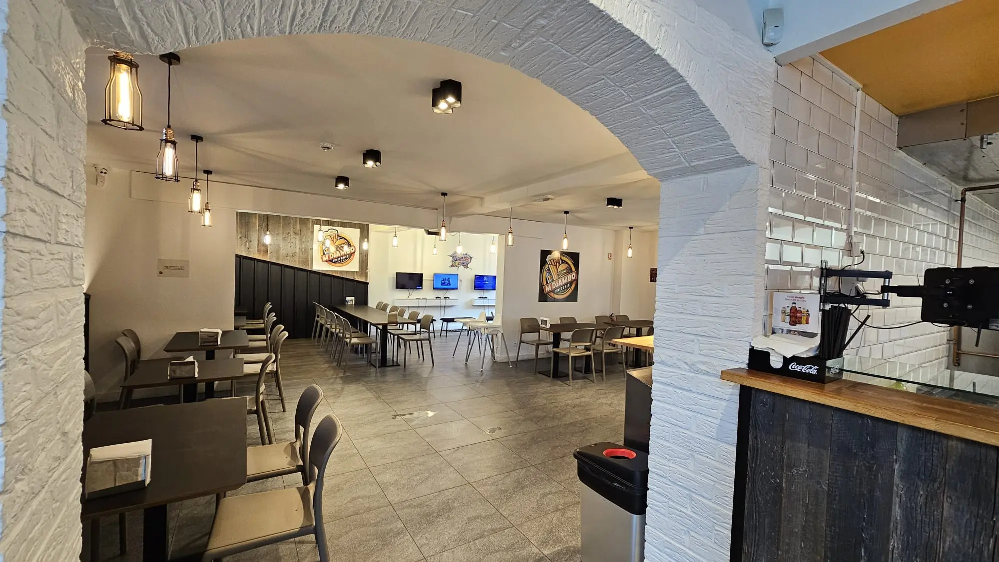 Intérieur restaurant moderne MDjambo Jurbise design industriel chic éclairage suspendu mur orange